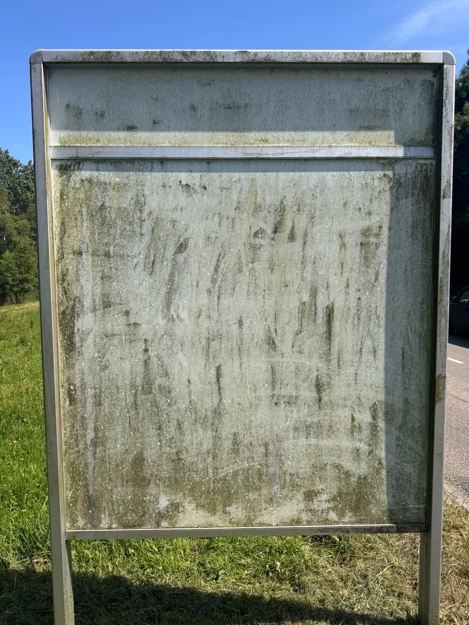 Reclamebord Weuste Noord in Wierden vóór de reiniging door CleanNL — groene aanslag